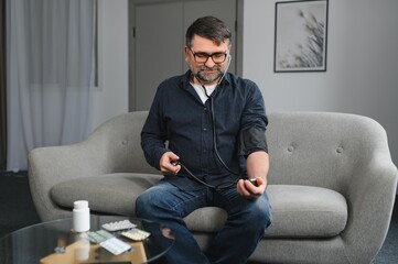 Senior man using medical device to measure blood pressure