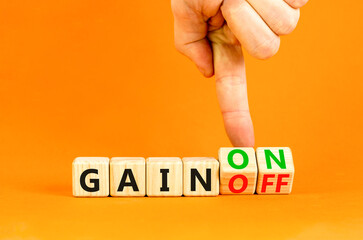 Gain on or off symbol. Businessman turns wooden cubes and changes word Gain off to Gain on. Beautiful orange table orange background. Business and gain on or off concept. Copy space.