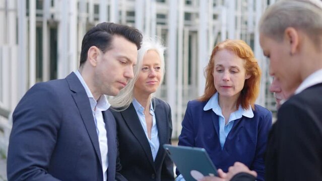 Worried business people looking the screen of a tablet outdoors