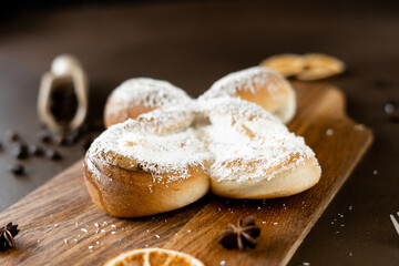 Sweet spiral Bun with Coconut chips and vanilla cream on wooden board. Bakery pastries on brown background. Close-up