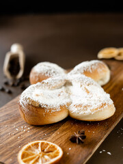 Sweet spiral Bun with Coconut chips and vanilla cream on wooden board. Bakery pastries on brown background. Close-up