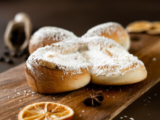 Sweet spiral Bun with Coconut chips and vanilla cream on wooden board. Bakery pastries on brown background. Close-up
