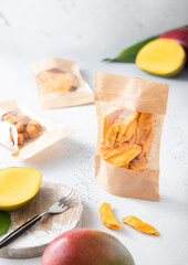 Various packages with sweet dried mango pieces and balls on light background.