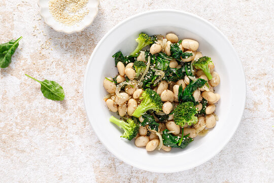 White beans stewed with spinach and onion, healthy vegan food, top view