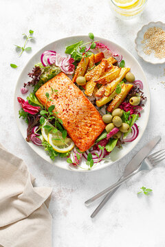Salmon fillet grilled, fried potato and fresh vegetable green salad, top view