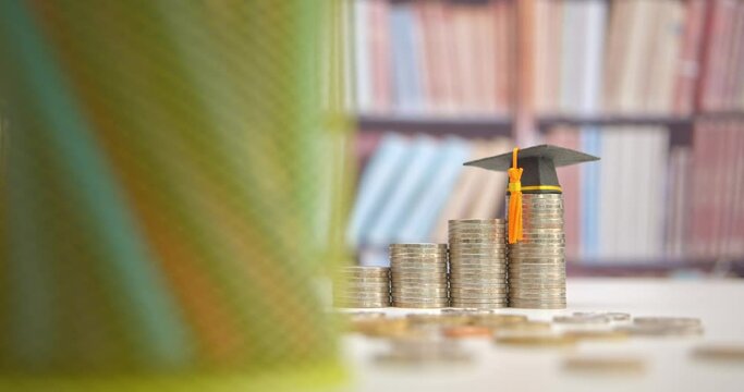 Tuition payment or tuition fee, expense for graduate study abroad program concept : Black graduation cap on stacks of coins, depicting fees charged by education institution for instruction or services
