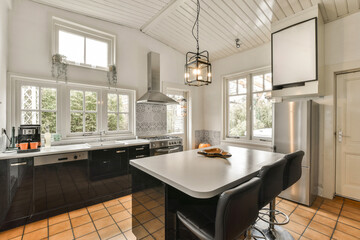a kitchen with black cabinets and white counter tops, an island style dining table is in the center of the room