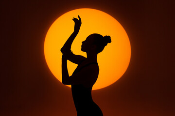 Silhouette of a gracefully dancing woman against the background of a circle of light. Frame up strip.