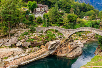 Fototapeta na wymiar Ancient double arch stone Roman bridge (Ponte dei Salti) over the clear water of the Verzasca river in Lavertezzo ,Verzasca Valley, Ticino Canton, Switzerland