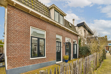 a brick house with a fence in the front and some trees on the other side of the home is empty