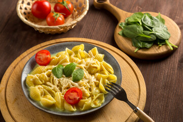 Pasta in cream sauce with cheese garnished with spinach with a fork on a round wooden stand.