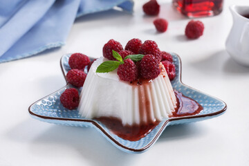 Sliced coconut vanilla panna cotta and jelly custard agar-agar pudding with fresh raspberry berries and sweet syrup on a plate. Selective focus, horizontal.