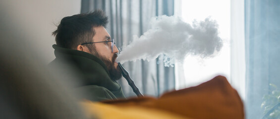 Banner bearded millennial or gen z man smoking hookah while relaxing on sofa at home copy space -...