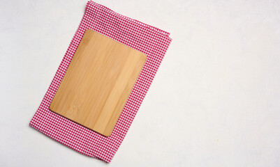 Empty wooden cutting board and red towel on white background. Copy space