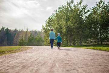 Two funny boys-brother and friend, walking together in the spring park, running, jumping and enjoying.