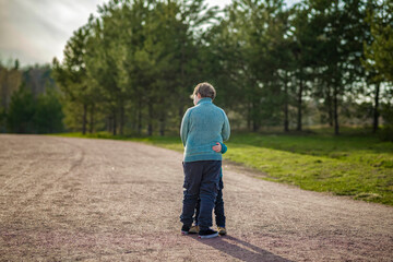 Two funny boys-brother and friend, walking together in the spring park, running, jumping and enjoying.