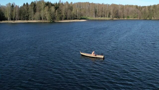 A lonely man oaring the boat at middle of lake.