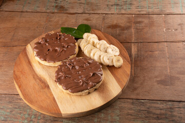 chocolate hazelnut cream waffle with banana slices on wooden board over top view landscape in close-up