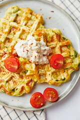 Snack waffles with bacon, cheddar cheese, spinach, sauce and cherry tomatoes on light background