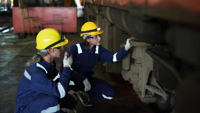 Team of engineers inspects and repairs the diesel locomotive in the maintenance workshop.