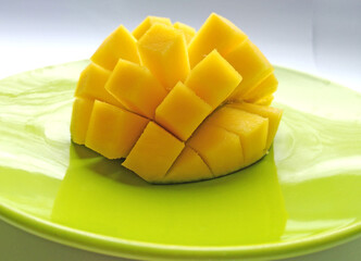 pieces of ripe sliced mango fruit on a plate. Closeup of fresh juicy tropical mango ready to eat healthy sweet dessert, vegan food.