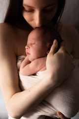 gentle close-up portrait of a mother with a newborn baby in her arms. photograph in a dark key, dark color. a happy family