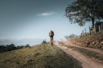 Fototapeta premium Homem mochileiro caminhando em direção ao acampamento. Espaço para texto.