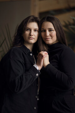 Family portrait, two lovely sisters, posing hugging, looking at the camera.