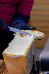 raclett cheese with hand and knife. Streetfood.