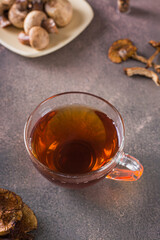 Homemade hot tea from dried mushrooms in a cup on the table vertical view