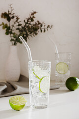 Sparkling mineral water with ice and lime in glasses for refreshment in the summer vertical view