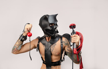A sexy man in bdsm wearing a demon mask with a whip wearing a leather cloak with leather handcuffs...