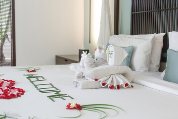 Welcome flowers and towels arrangement on the bed in luxury hotel on arrival.	