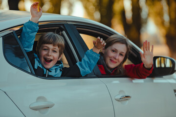 Happy mother and son waving hands from car window