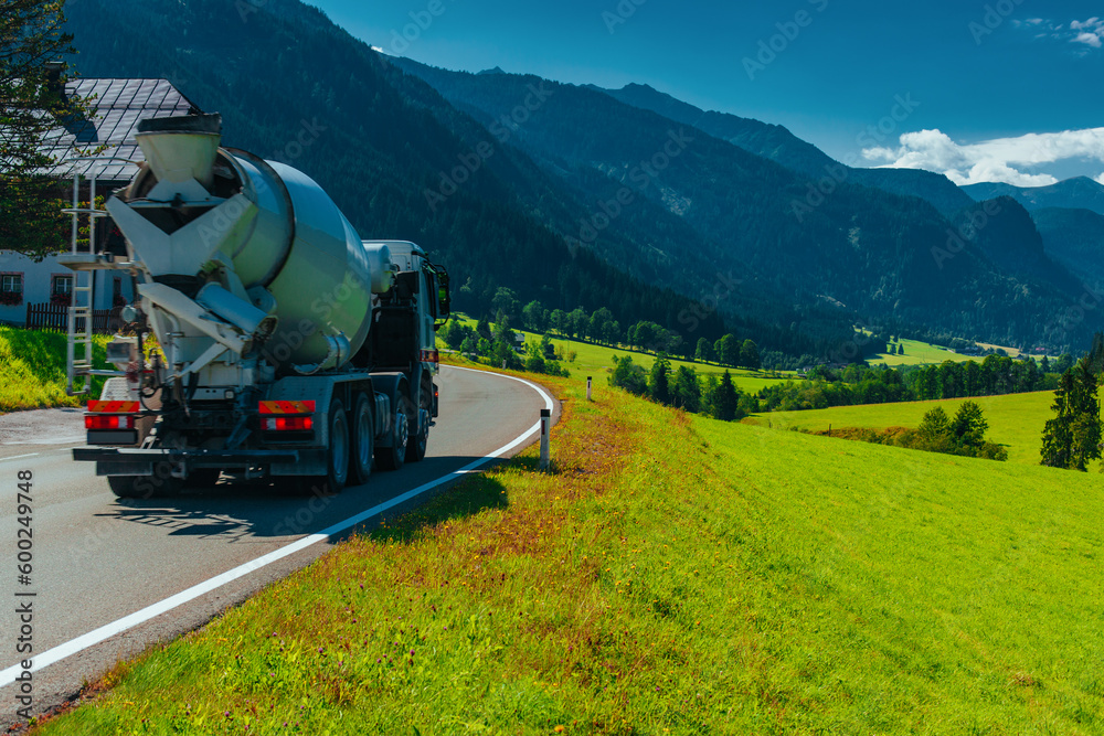 Wall mural concrete mixer truck drives on beautiful road in alps