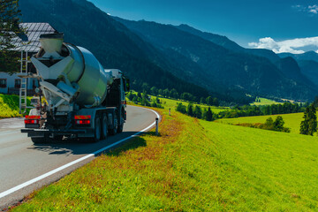 Concrete mixer truck drives on beautiful road in Alps