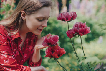 Fototapeta premium Portrait of young beautiful woman with poppies in the garden