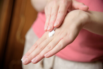 Girl applies cream on her hands.