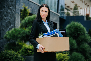 An office worker standing outside with a box, portraying the loss of their job and work. The...
