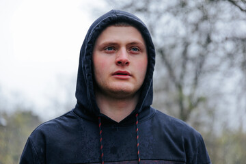 Mysterious Guy with Handsome Portrait in Rainy Outdoor. A young man's portrait in the rain captures his rugged and handsome features. © Alexandr