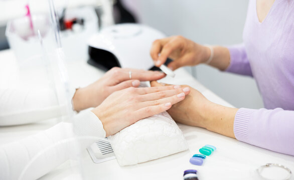 Woman hands in a nail salon, which the manicure master gives shape to the nails with a nail file. Close-up image