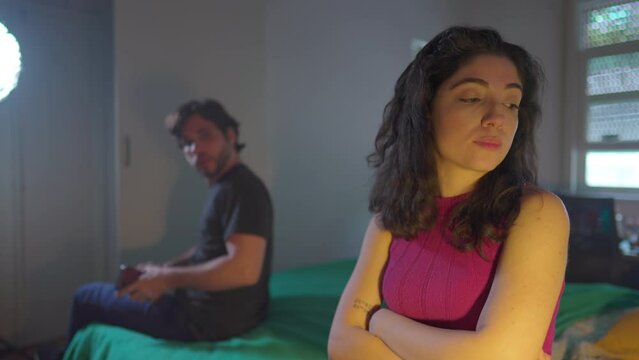 Upset woman crossing arms ignoring male partner both sitting by bedside in bedroom. Uncommunicative Girlfriend dismissing boyfriend