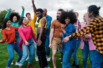 Fototapeta premium Group of friends from diverse cultures dancing and singing together outdoors. Concept: pride, freedom, fun