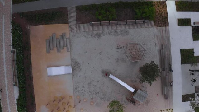 Person on playground in courtyard of modern houses. Stock footage. Top view of modern playground in residential complex. Modern landscape of residential area with playground