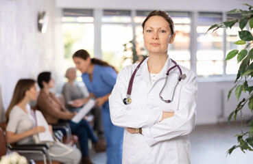 Adult woman in medical uniform with stethoscope posing in clinic reception