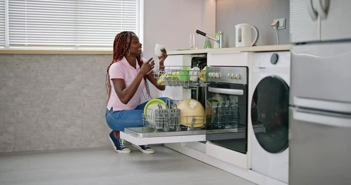 Young Happy Woman Arranging Plates In Dishwasher