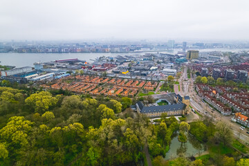 beautiful scenic drone shot of Amsterdam Center, green trees houses and a port on the river. High quality photo