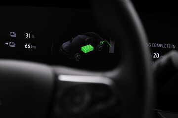 Close up electric car charger screen display with isolated steering wheel inside car. Selective...