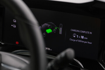 Close up electric car charger screen display with isolated steering wheel inside car. Selective focus of screen dispaly. 