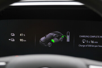 Close up electric car charger screen display with isolated steering wheel inside car. Selective focus of screen dispaly. 